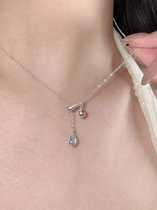 Detail of S925 silver Y-shaped necklace with light blue pear-cut sapphire pendant on model