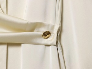 Gros plan sur la texture du satin crème et un bouton en métal doré élégant