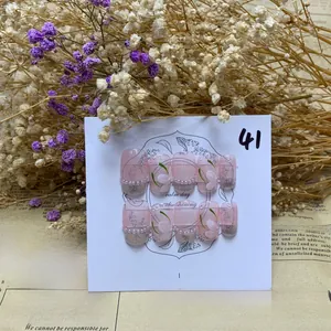 Detailed view of handmade pink French press-on nails with white flowers and pearls