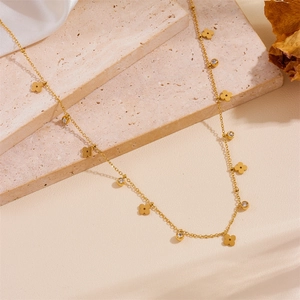 Detailed close-up of gold titanium steel necklace with clover charms on stone background