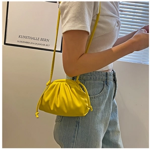 Detail view of yellow ruched dumpling bag with thin round straps and soft pleated design