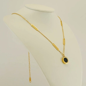 Detail of 18K gold-plated necklace with double-sided black pendant on a model