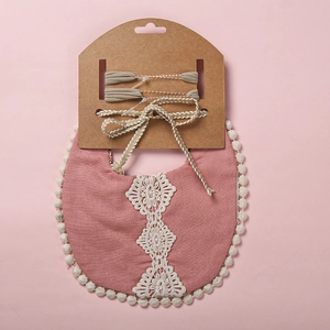 Vue détaillée du bavoir rose avec fleurs en dentelle blanche et bordure à petits pompons