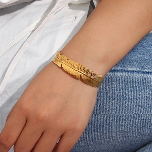 Macro shot of 18K gold plated leaf-shaped open bangle showing detailed brushed texture