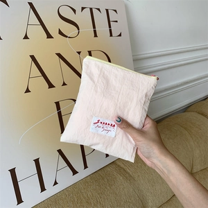 Detail of light pink pleated fabric cosmetic pouch with SOZAKKA label held in hand