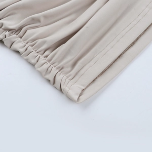 Détail de la robe beige à épaules dénudées montrant les coutures fines et le tissu plissé