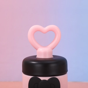 Close-up of pink insulated cup lid featuring a heart-shaped handle and bow detail