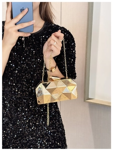 Close-up of golden geometric evening clutch bag with metallic chain and glossy facets