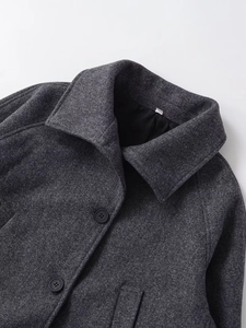 Detailed close-up of dark gray wool blend coat with lapel collar and black buttons