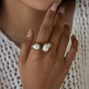 Detailopname van 18K vergulde open ring met twee barokke parels gedragen aan de vinger
