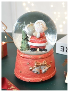 Close-up of a vintage Santa Claus music snow globe with a red embossed base and snowflakes