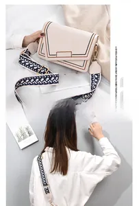 Detail of cream flap crossbody bag featuring geometric wide strap and contrast stitching