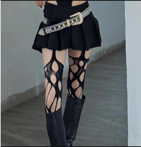 Close-up of irregular distressed black fishnet stockings with Y2K punk style details