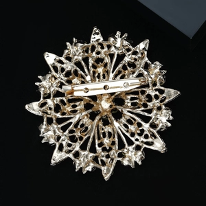 Detailed close-up of golden sunflower brooch with intricate filigree on black background