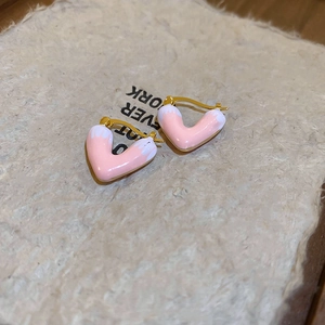 Close-up of pink heart drip oil earrings on textured beige paper background