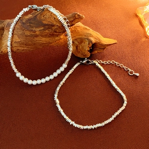 Minimalist silver bead and pearl layered bracelet set displayed on a wooden prop