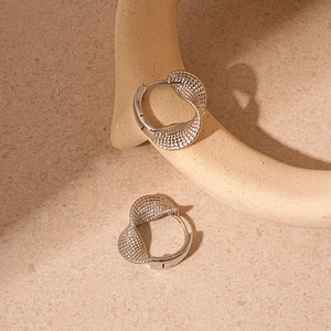 Detailed close-up of silver twist texture hoop earrings on a minimalist background