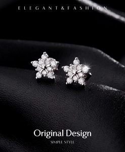 Macro shot of silver snowflake moissanite earrings with sparkling diamonds on leather