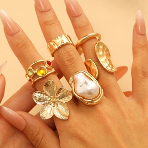 Baroque style gold ring set with vintage flower motifs and pearl accents on hand