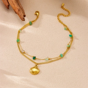 Detail of double-layer gold anklet with green stone beads and seashell pendant