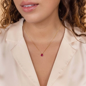 Elegant gold chain necklace with a pear-cut ruby gemstone pendant worn by a model