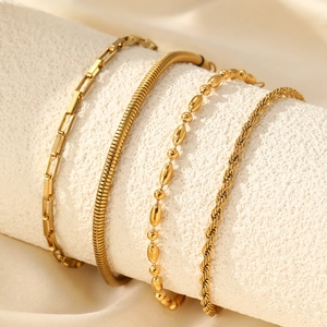 Close-up of four-piece gold chain bracelet set including snake and link styles