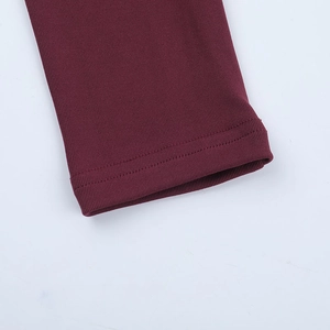 Macro shot of vertical ribbed knit texture and premium double stitching on burgundy top