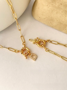 Detail of gold paperclip chain necklace with zircon Letter D and cross pendants