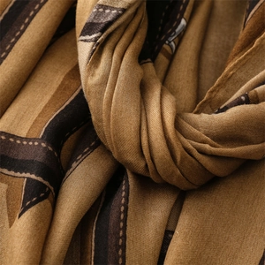 Macro shot showing soft cotton-linen texture and brown striped pattern of the scarf