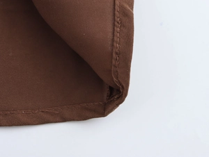 Detailed view of the brown chiffon fabric texture and high-quality stitching on the elegant dress