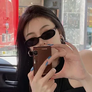 Fashionable black oval sunglasses with flat narrow frame shown on model in Y2K street style