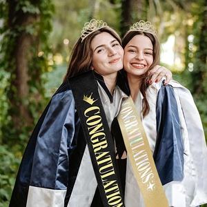 Close-up of graduates wearing rhinestone GRAD tiaras and CONGRATULATIONS sashes