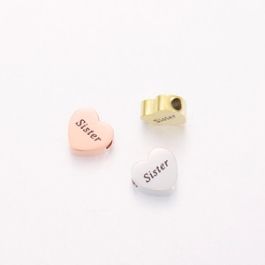 Three heart-shaped metal charms in rose gold, gold, and silver with Sister engraving