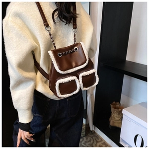 Detalle de mochila vintage marrón oscuro con ribete de piel sintética y cadena metálica