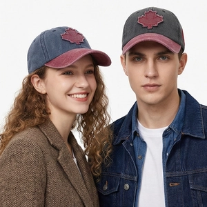Detail of 3D embroidered maple leaf on washed denim baseball caps worn by models