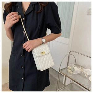Close-up of a white quilted crossbody phone bag with a gold metal turn-lock and chain strap