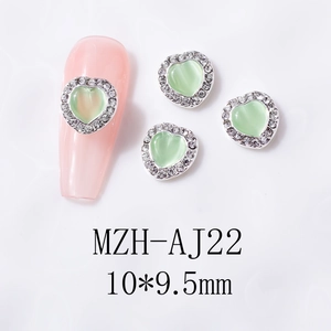 Detail of heart-shaped opal nail charm with white rhinestones on pink nail tip