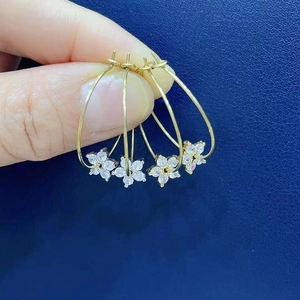 Macro view of gold-plated flower earrings with micro-inlaid zircons held by hand