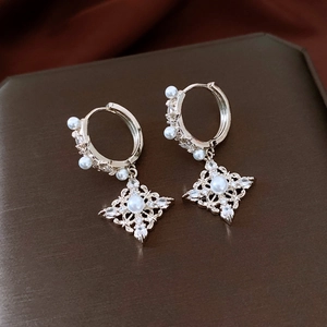 Vue macro des boucles d'oreilles dorées 18K avec pendentif losange et perle