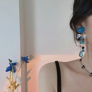 Close-up of long tassel earrings with blue heart and butterfly charms on model