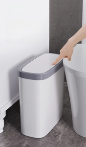 Detail of white slim trash can with grey press-top lid in a narrow bathroom space