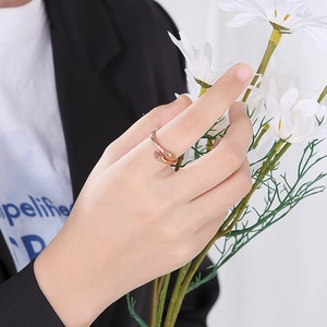 Close-up of rose gold hugging hands ring on finger with white daisy background