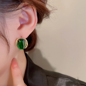 Detailed view of model wearing vintage emerald zircon earrings with gold plating finish