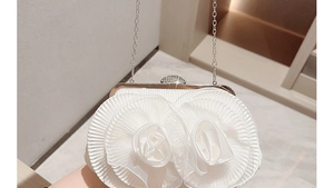 Close-up of white floral evening bag with pleated fabric and rhinestone silver chain