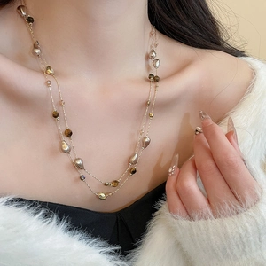 Close-up of dual-layer 18k gold-plated necklace with tiger eye and pearl beads on model