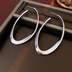 Detailed view of large oval irregular silver hoop earrings with a polished glossy finish