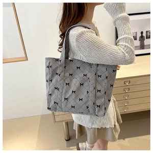 Close-up of grey corduroy tote bag featuring quilted rhombus patterns and black bow details