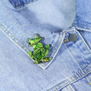 Detail of a green acrylic frog brooch with rhinestones on a denim shirt collar