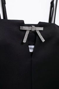 Détail du nœud en strass argenté sur la robe en satin noir à col en V