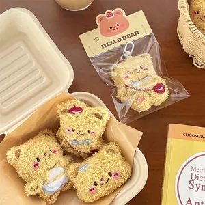 Cute plush yellow bear keychain with embroidery and Hello Bear packaging on wooden table